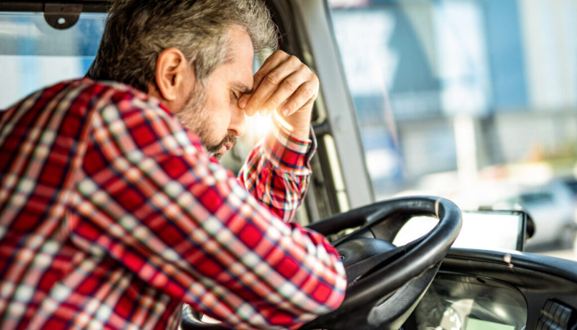 Tired mature truck driver waiting in traffic and contemplating about job problems.